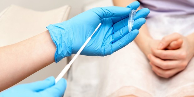a medical professional with blue gloves holds an STI test 