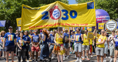People marching under the yellow 2030 Terrence Higgins Trust banner.