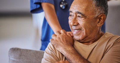older man with a nurse's hand on his shoulder