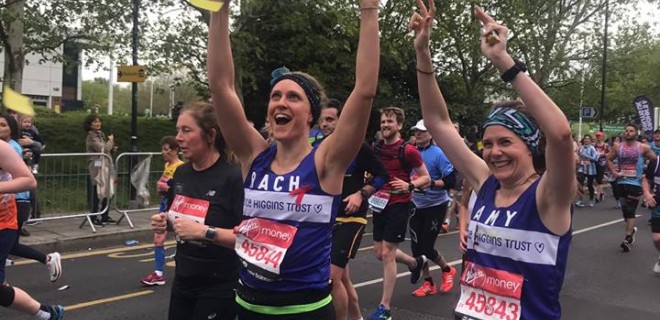 Two celebratory Terrence Higgins Trust marathon runners with their arms up in the air.