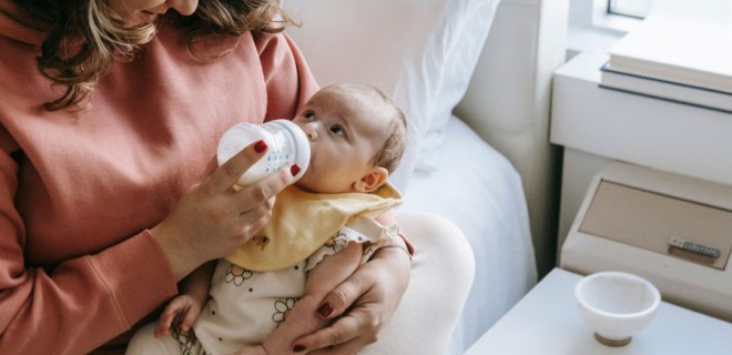A woman feeds a baby with a bottle.