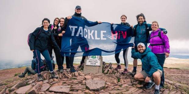 Gareth Thomas and other mountain climbers at the summit with a "Tackle HIV" banner.