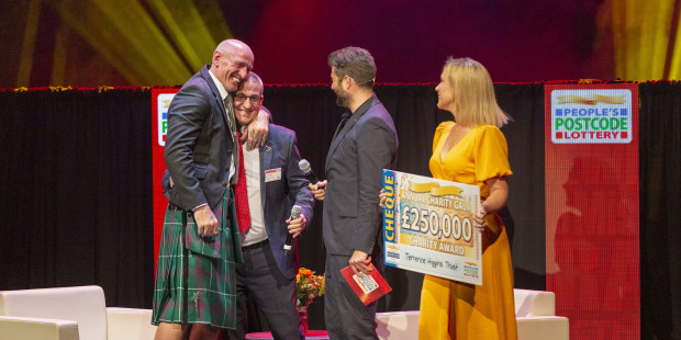 Gareth Thomas on stage with Ian Green at People's Postcode Lottery Charity Gala getting Postcode Hero award