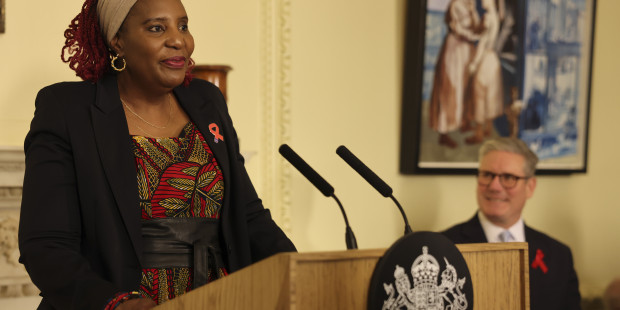 Memory Sachikonye delivering a speech with Keir Starmer in the background.