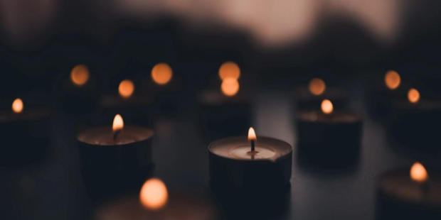 Lit tealight candles on a dark background.