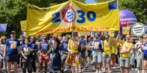 People marching under the yellow 2030 Terrence Higgins Trust banner.