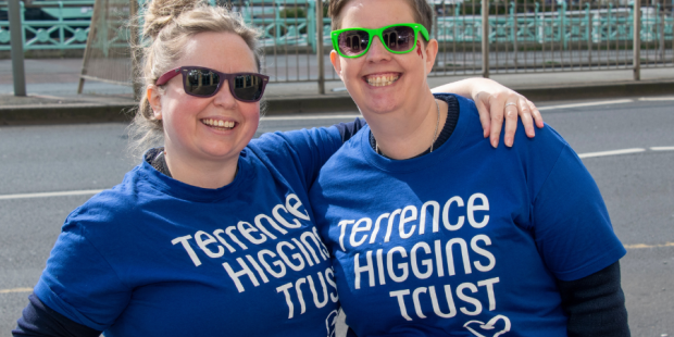 Two people in Terrence Higgins Trust t-shirts standing outside.