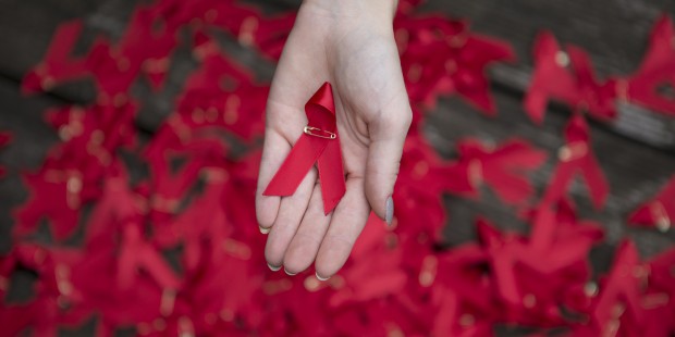 One hand holding one red ribbon