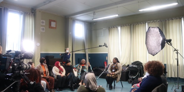 Image of a group of women of Black African and Caribbean heritage in discussion with a sexual health nurse. Recording equipment can be seen in the shot. 