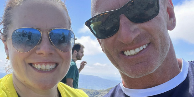 Christine with Gareth Thomas on the summit with blue sky behind them