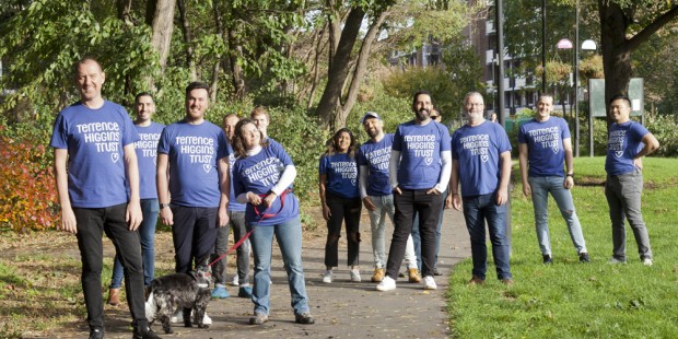 Large group of Ribbon Walk people in THT shirts in park with dog