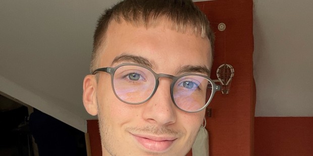Dylan smiling indoors wearing red ribbon