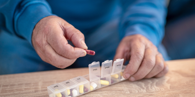 A older person uses a pill box