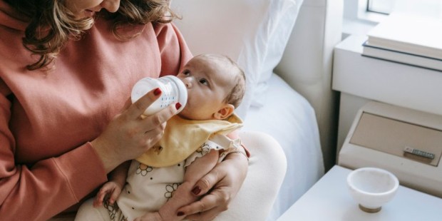 A woman feeds a baby with a bottle.