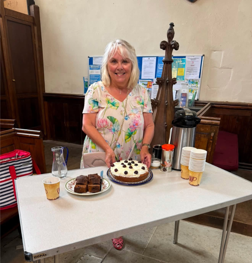 A woman stands behind a table with cakes in front of her.